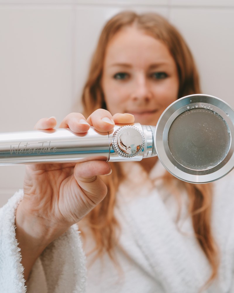 Frau hält den WaterJake® Duschkopf 3.0 in die Kamera